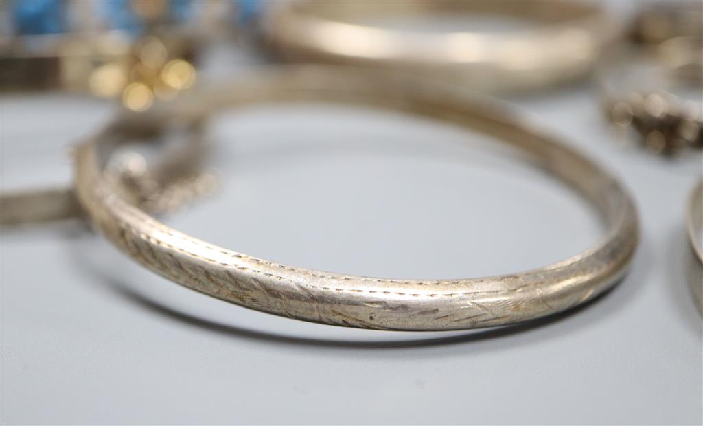 Eleven assorted silver or white metal bangles.